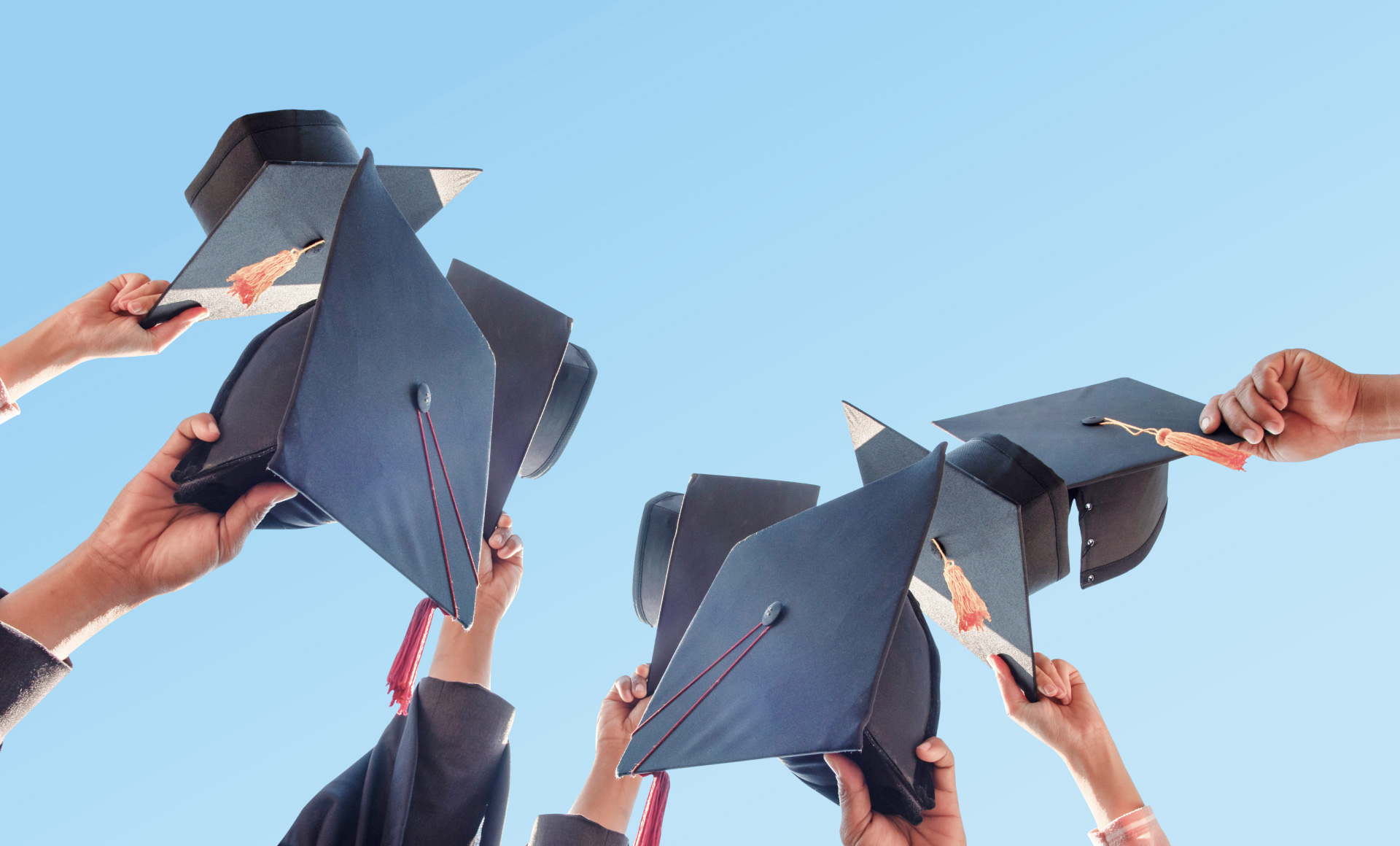 a photographic image of a large number of people lifting their graduation caps.